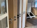 Showroom mit Türen in verschiedenen Farben und Griffen, zeigt Auswahl moderner Bauelemente.